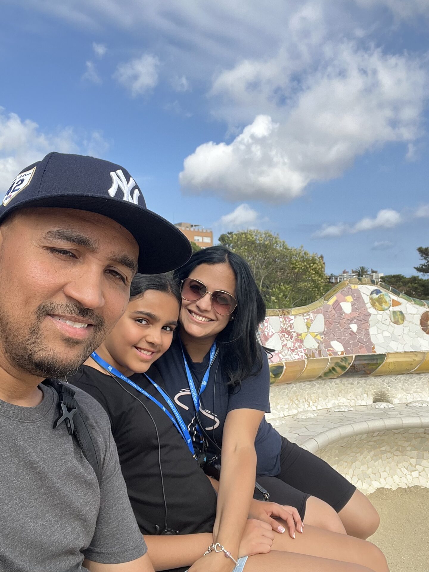 man girl and woman in park Guell, sitting on bench with Gaudi mosaic design.